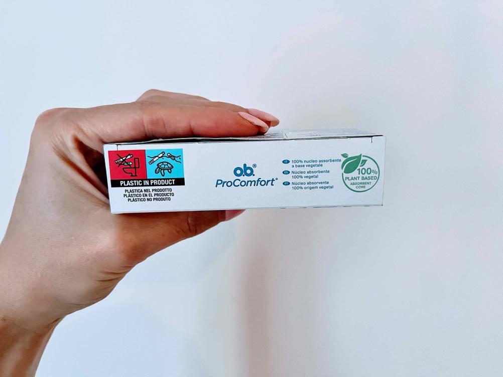 Tampon getestet: Eine Hand hält eine Packung seitlich vor eine helle Wand.