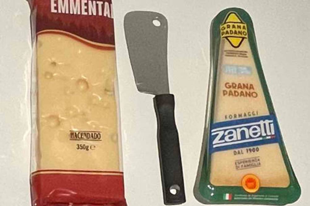Käsemesser getestet: Ein Messer liegt zwischen zwei unterschiedlichen verpackten Käsen