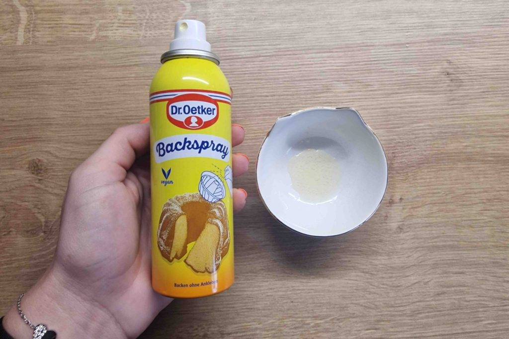 Backtrennspray-Test: eine Dose Backtrennspray wird neben einem Schüsselchen gehalten, worin sich Backtrennspray befindet.