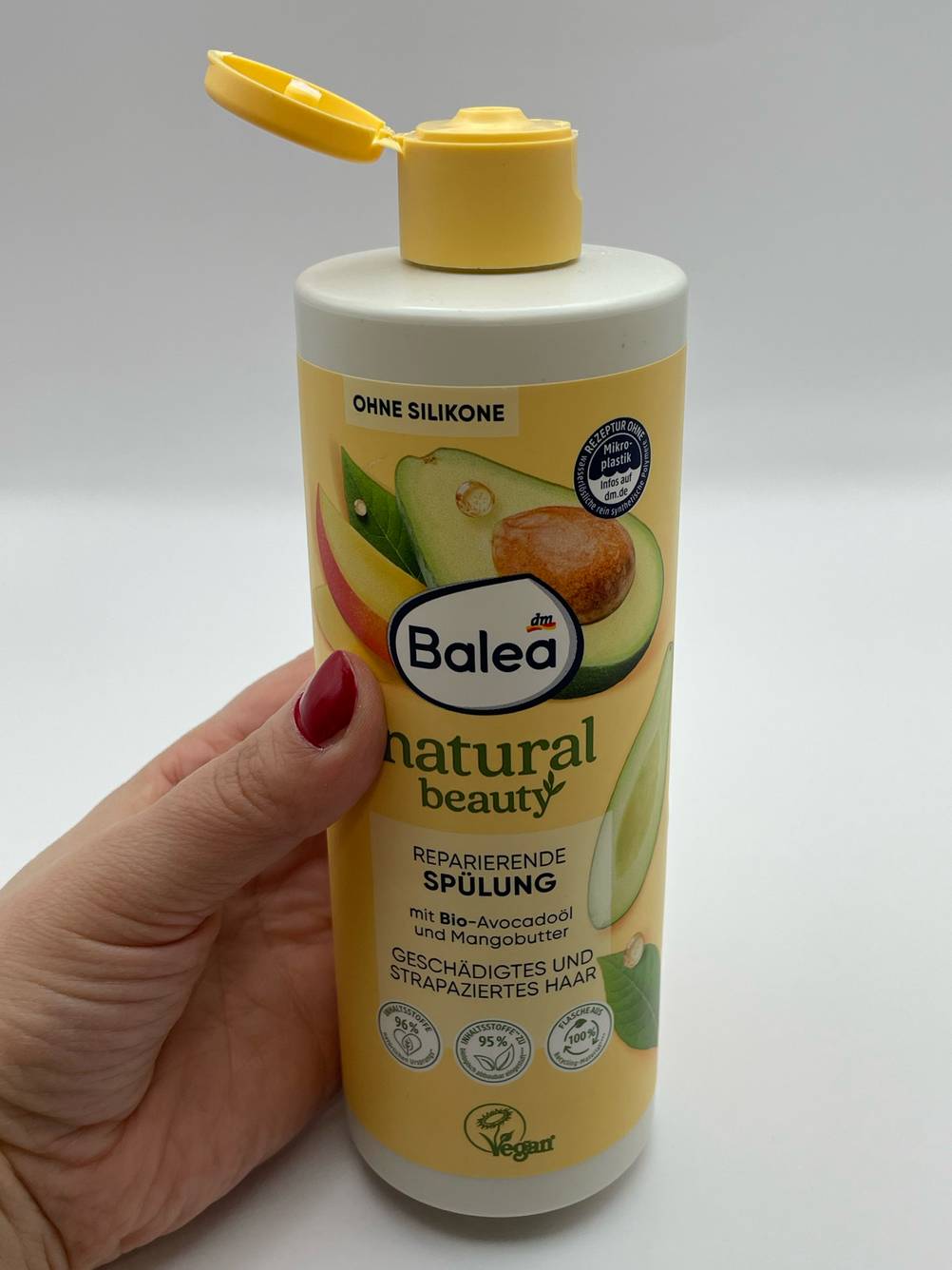 Die geöffnete Flasche des getesteten Haarbalsams wird in der Hand gehalten.