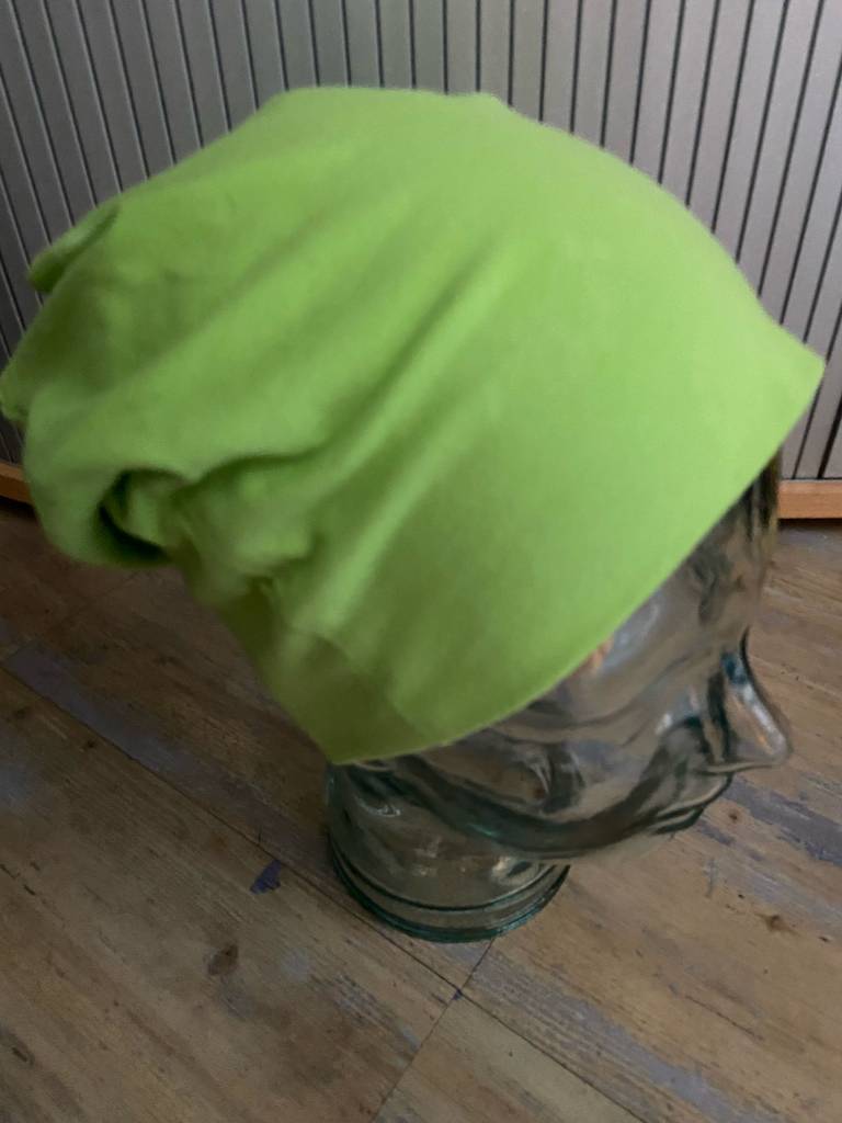 Beanie getestet: Ansicht von seitlich oben auf die grüne Mütze, die auf einem Glaskopf ausgestellt ist.