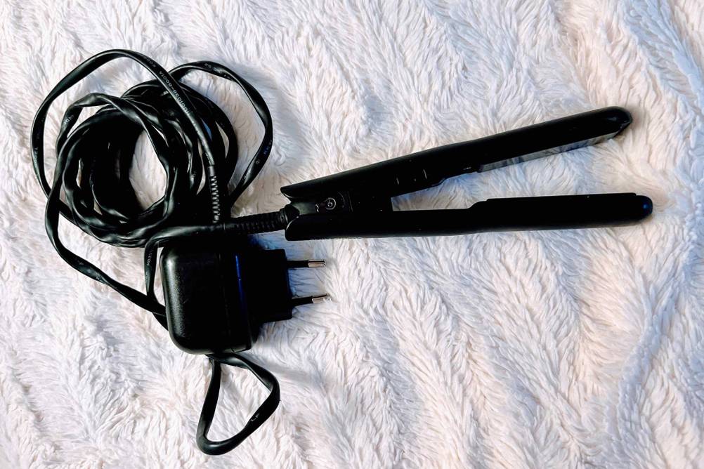 Mini-Glätteisen im Test: Das Glätteisen liegt inklusive seines Stomkabels auf einem hellen Stoff