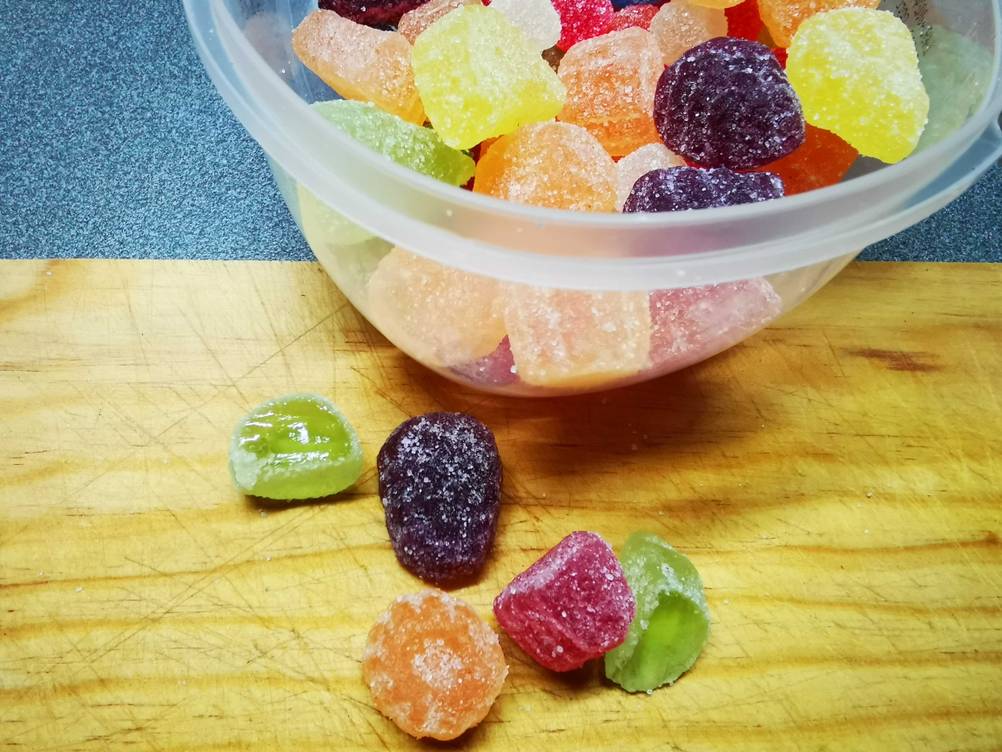 Ein teil der getesteten Geleefrüchte liegt vor einer Plastikbox und der andere Teil davor.
