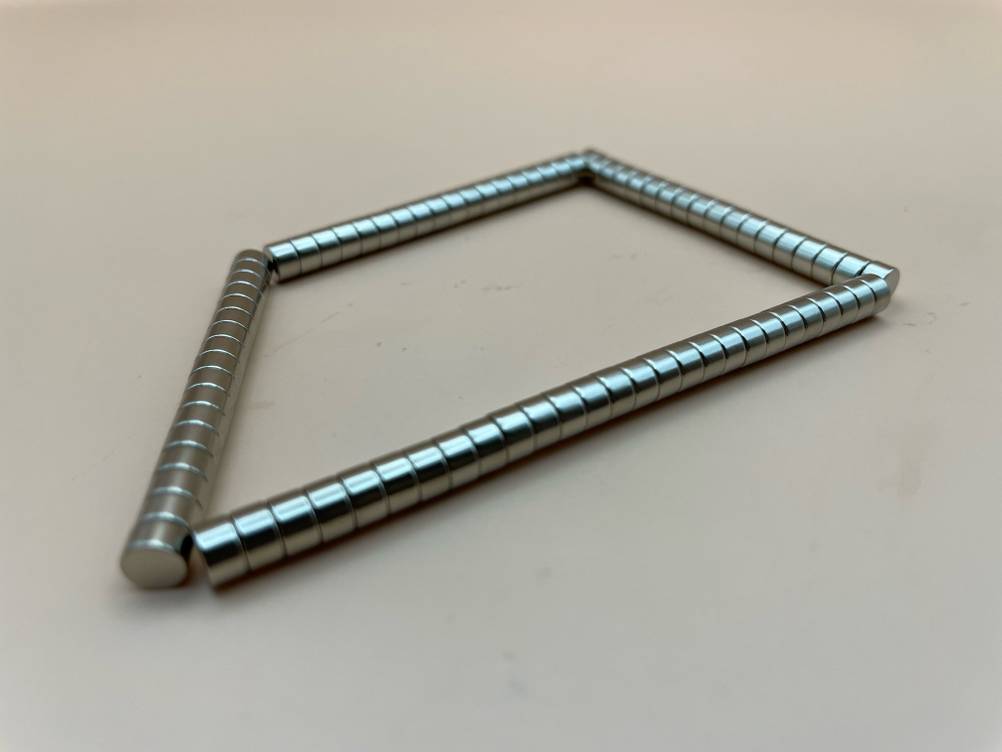Mehrere aneinander gekettete Kühlschrankmagnete die getestet wurden, werden auf einer hellen Fläche präsentiert.