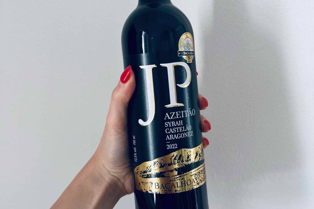 Rotwein (lieblich) im Test: Eine Hand hält eine Flasche vor eine helle Wand