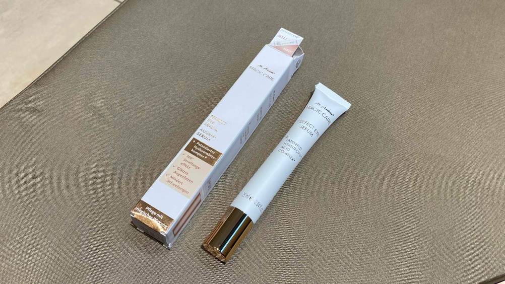 Ein getestetes Augenserum liegt neben seiner Verpackung auf einem beigen Boden.