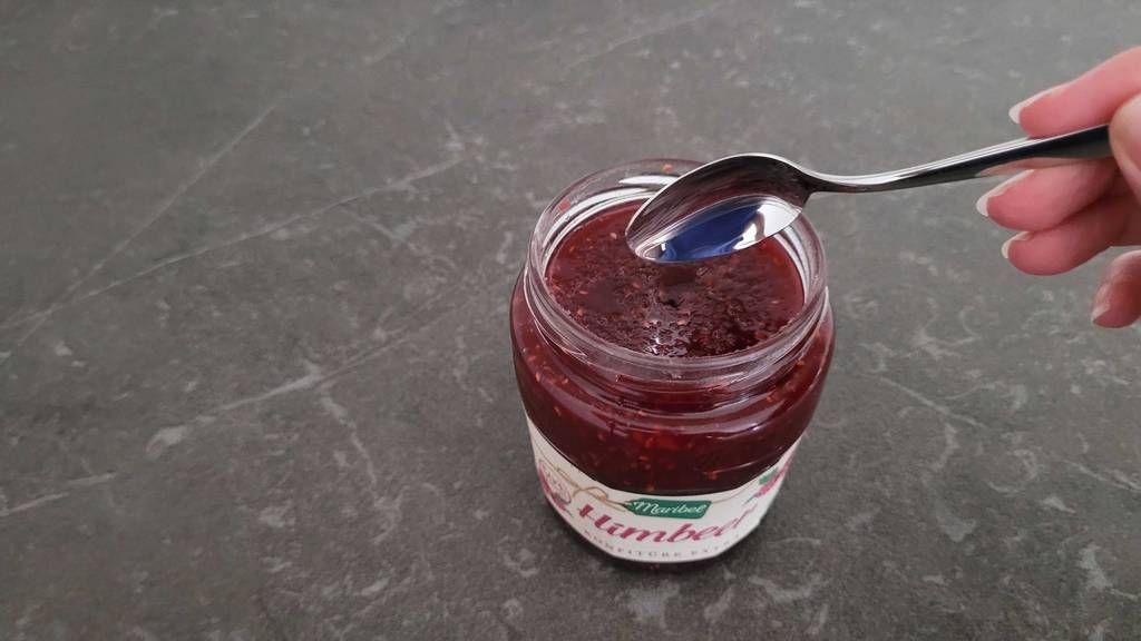 Himbeermarmelade und Löffel zu sehen.