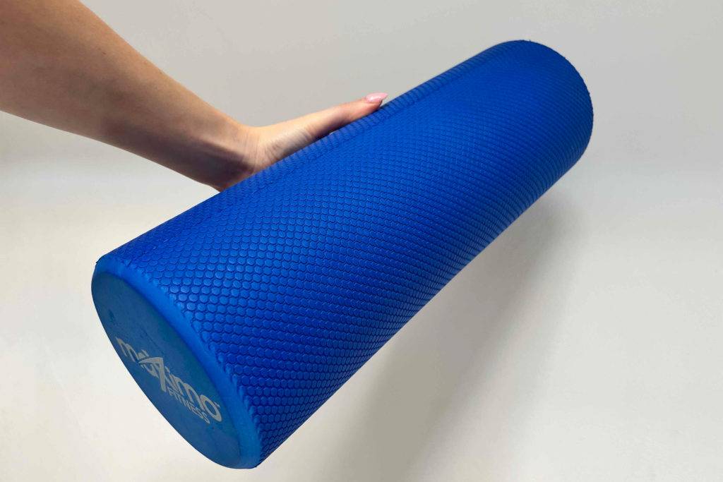 Massageroller im Test: Eine Hand hält eine blaue Massagerolle vor eine helle Wand