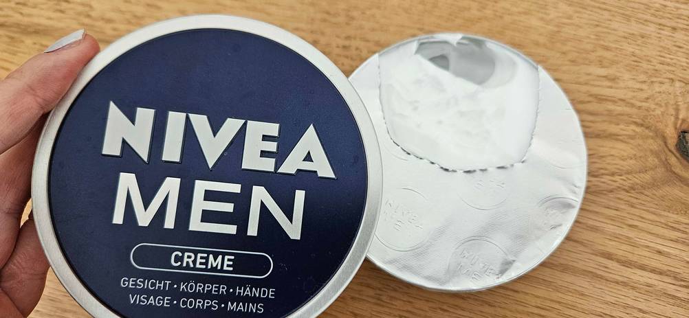 Im Test: Eine Hand hält den Deckel der Gesichtscreme Herren im Hintergrund steht die Dose.