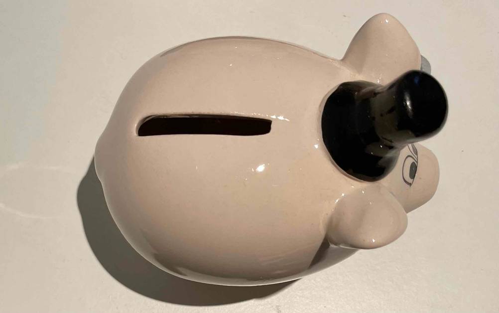 Sparschwein getestest: Ein Schwein mit Zylinder von oben auf einer hellen Fläche.