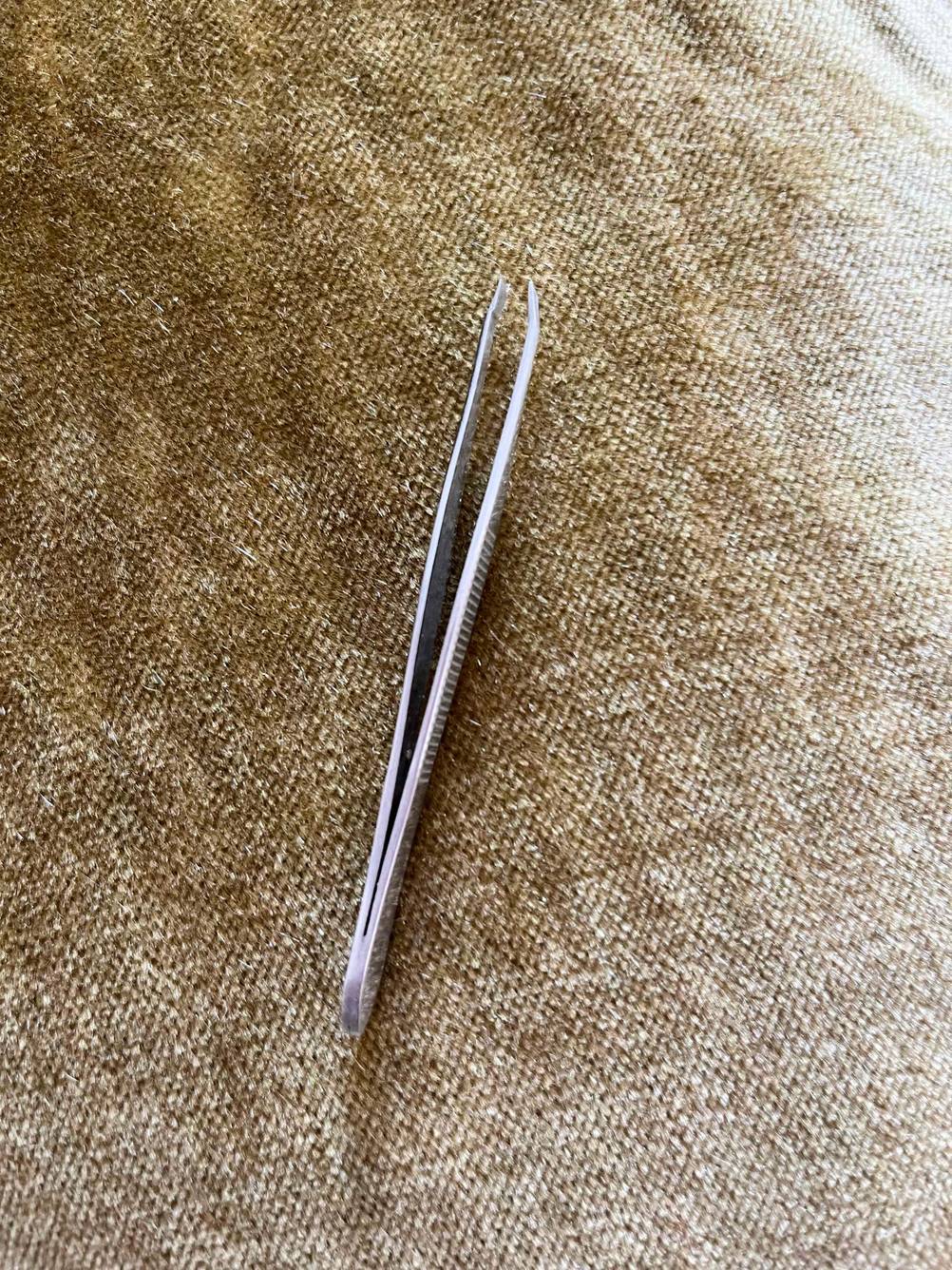 Im Test: Eine Pinzette von oben auf einer beigen Fläche.