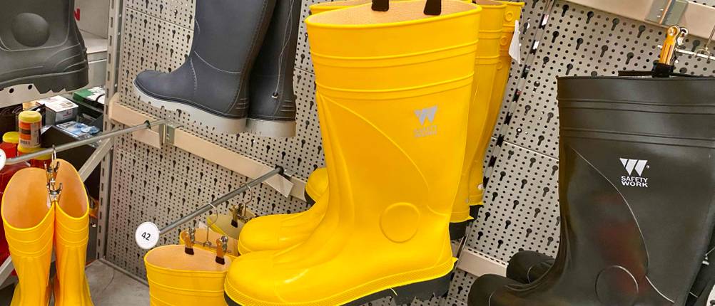 Gummistiefel-Herren-Test: mehrere Gummistiefel in schwarzer und gelber Farbe hängen in einem Regal.