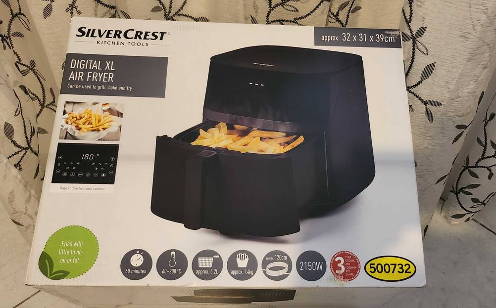Die Verpackung der getesteten Heißluftfritteuse mit Grillfunktion von vorn ersichtlich, während darauf verschiedene Informationen zum Produkt abgebildet sind.