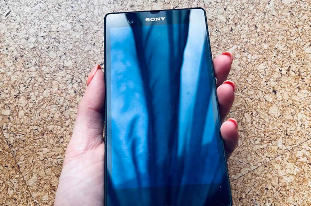 Eine Hand hält ein getestetes Sony-Smartphone vor eine Holzfläche.