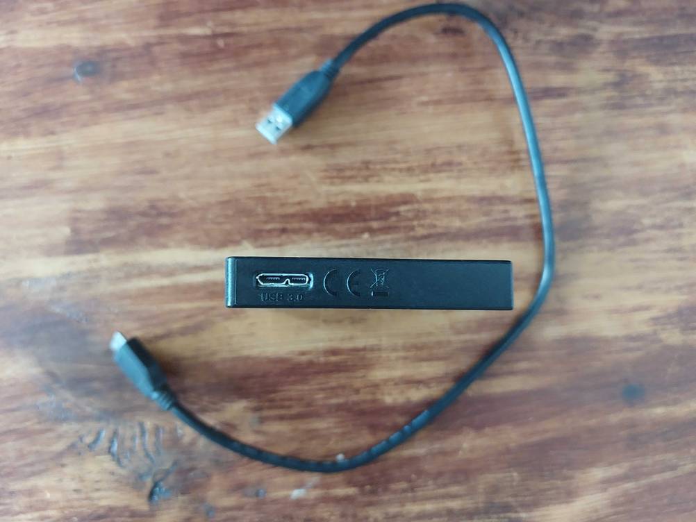 Eine getestete SSD-Festplatte seitlich mit Anschluss und Kabel.