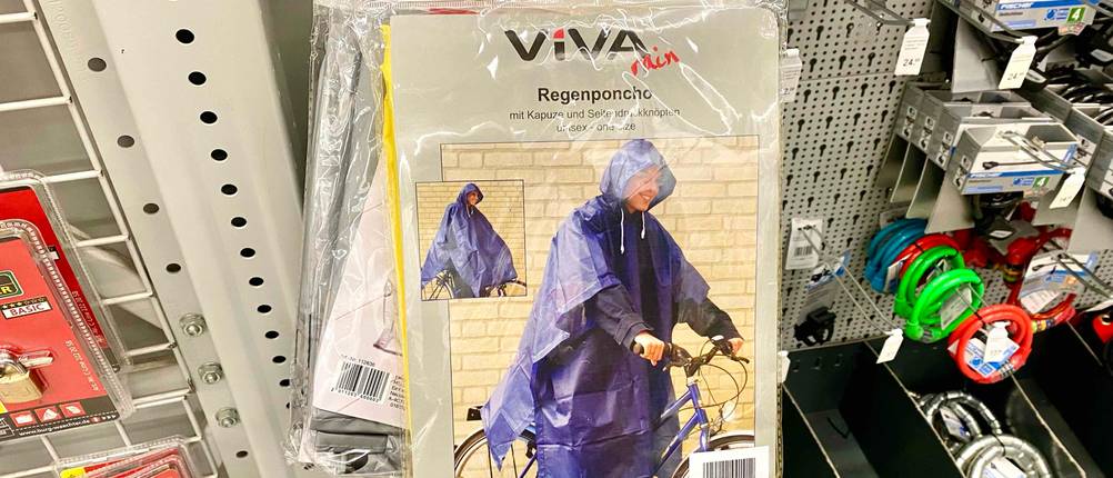 Regenponcho im Test: mehrere Regenponchos hängend in einem Regal neben anderen Produkten.