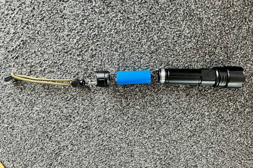 Im Test: Eine 10.000-Lumen-Taschenlampen in ihre Einzelteile zerlegt auf einem grauen Teppich.