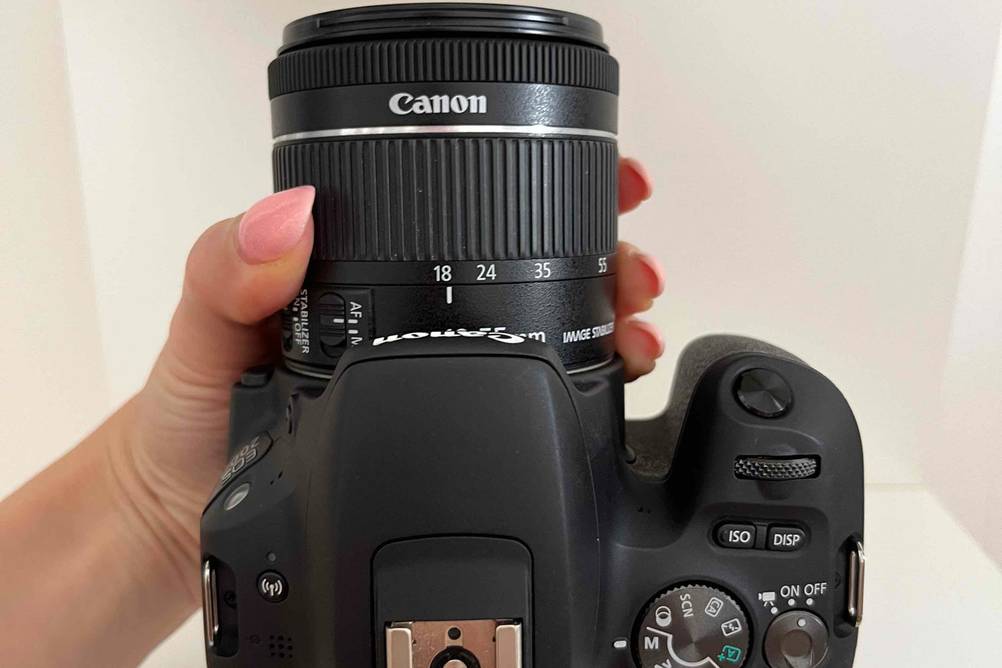 Canon-Systemkamera im Test: Die Kamera wird von einer Hand am Objektiv vor eine helle Oberfläche gehalten