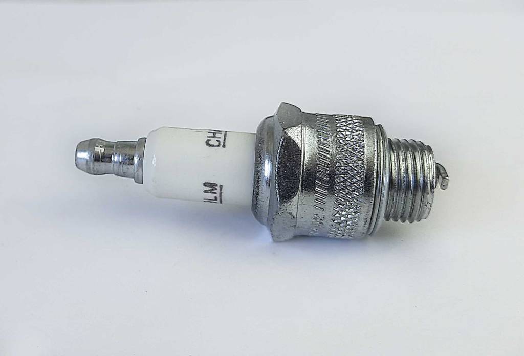 Im Test: Die Rasenmäher-Zündkerze liegt auf einer weißen Oberfläche.