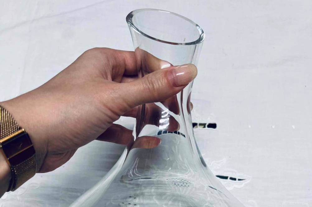 Weinbelüfter getestet: Eine Hand hält einen Weinbelüfter vor eine helle Tischdecke.