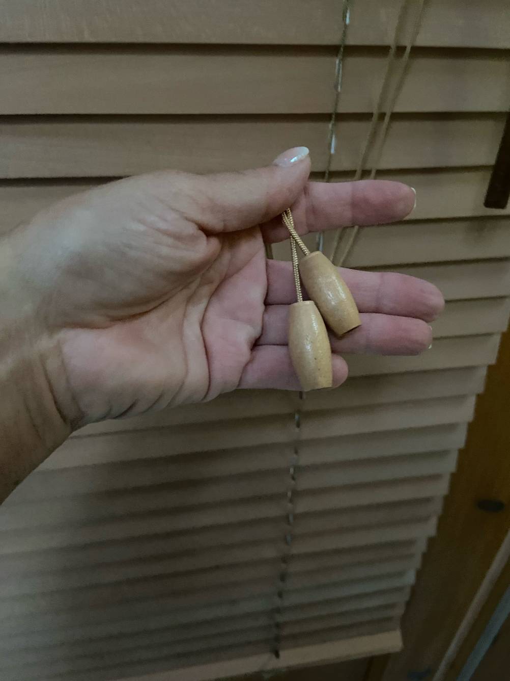 Die Schnur der getesteten Holzjalousien, mit welchen man die Jalousien nach oben und unten ziehen kann, wird in der Hand gehalten.