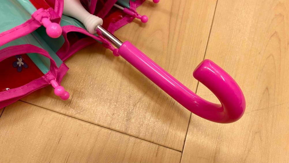 Pinkfarbener Griff des getesteten Kinder-Regenschirms liegt auf dem Boden.