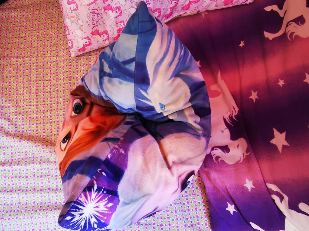 Kinderkissen im Test: Ein Modell, bedruckt mit Comicfiguren, liegt auf einer bunten Oberfläche.
