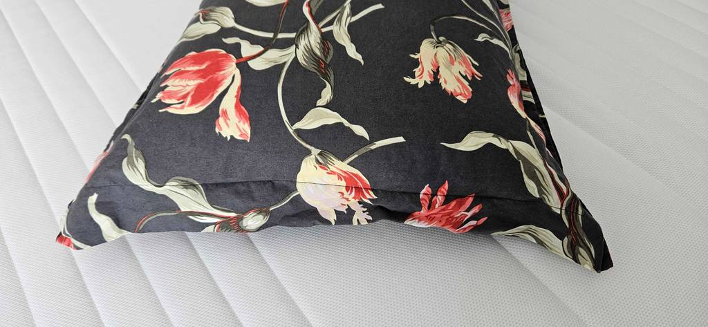 Kopfkissen-40x60 im Test: Ein überzogenes Kopfkissen mit Blumenmotiven liegt auf einem Bett.