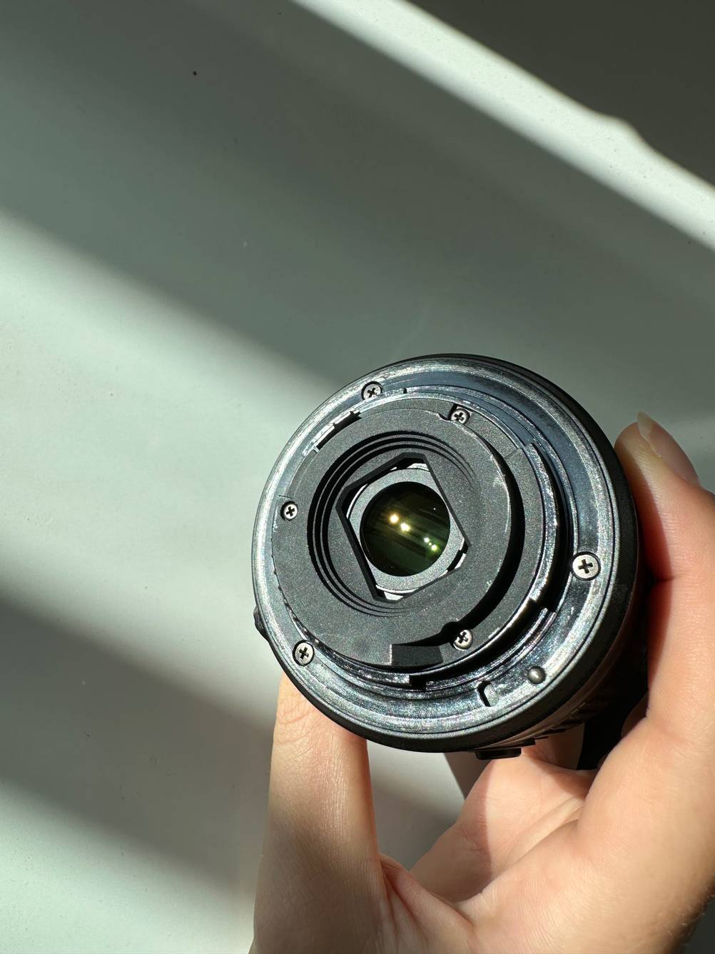 Im Test: Das Bajonett eines Objektivs für Nikon von einer Hand vor eine helle Fläche gehalten.