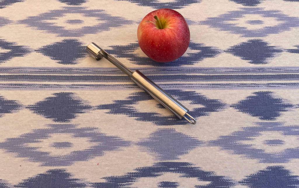 Apfelausstecher im Test: Ein Ausstecher liegt neben einem Apfel auf einer Tischdecke