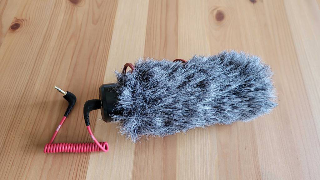 Richtmikrofon im Test: Richtmikrofon mit flauschigem Überzug liegt auf einem Holzuntergrund.