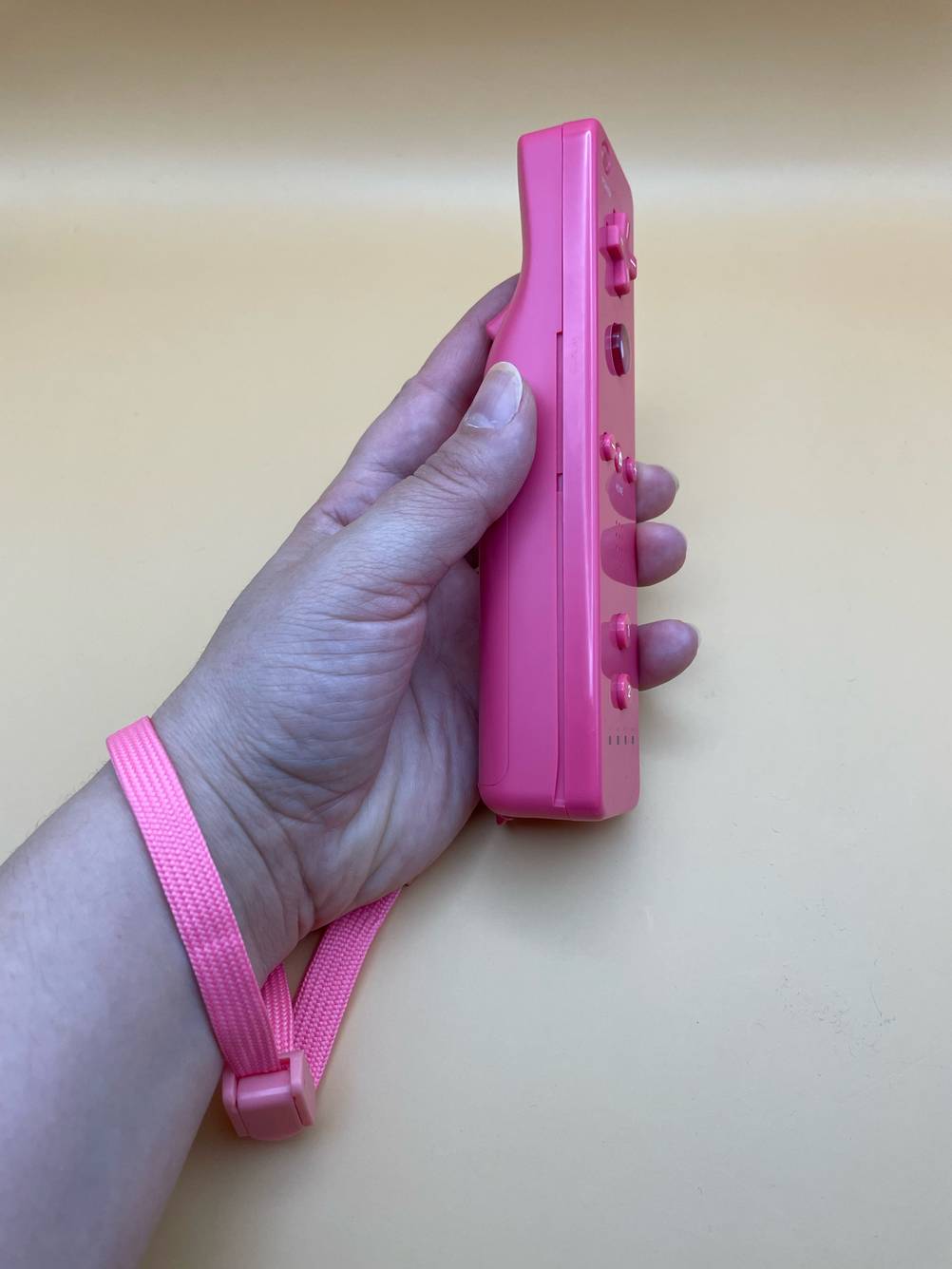 Der getestete Nintendo-Wii-Controller wird mit dem Handgelenkband in der Hand gehalten.