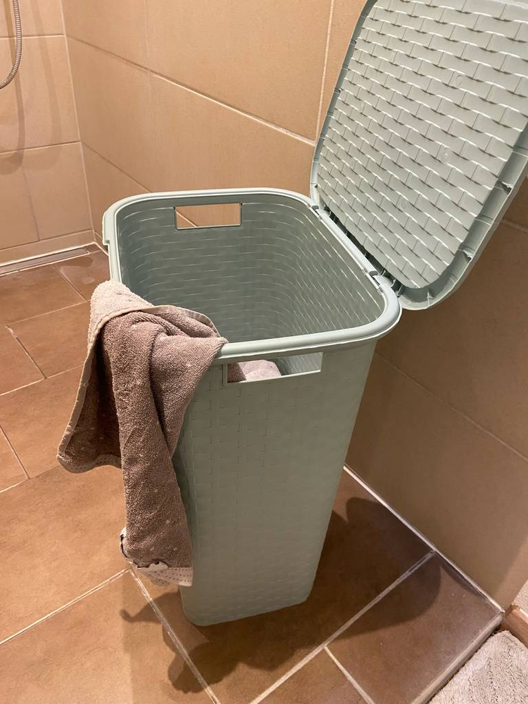 Ein geöffneter Wäschesammler im Test steht inklusive einem beigefarbenen Handtuch im Badezimmer.