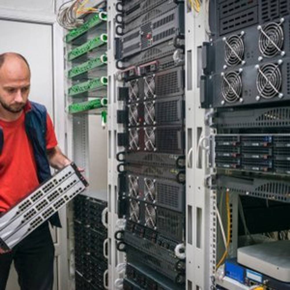 Techniker, der Switches in ein Rack in einem Serverraum oder Verteilerraum einsetzt