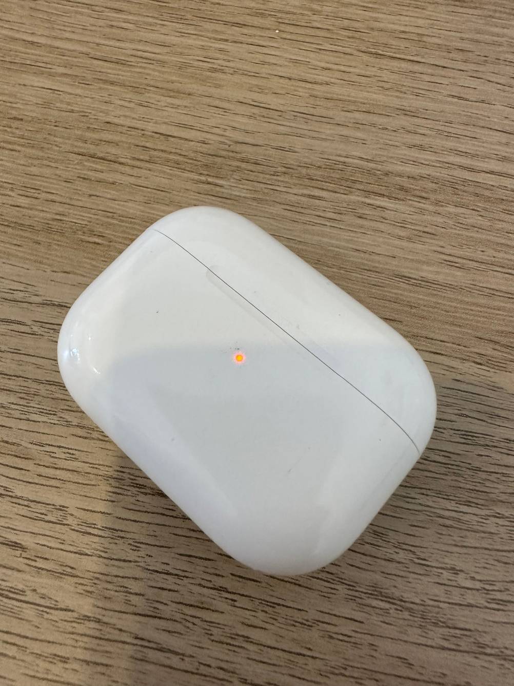 Im Test: Case mit roter Leuchte der True-Wireless-In-Ear-Kopfhörer auf einer Holzfläche.