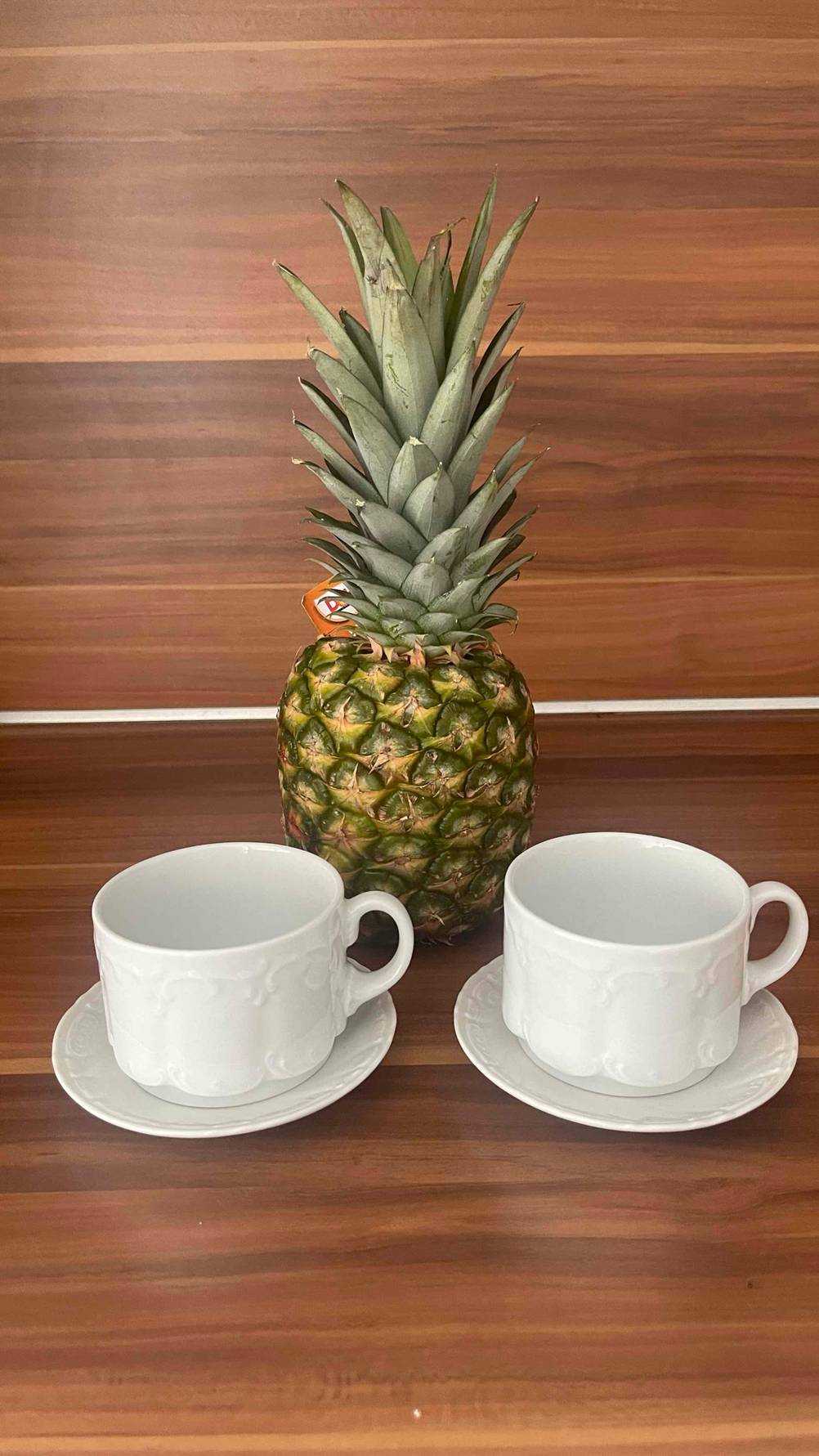 Zwei getestete Cappuccino-Tassen stehen vor einer Ananas.