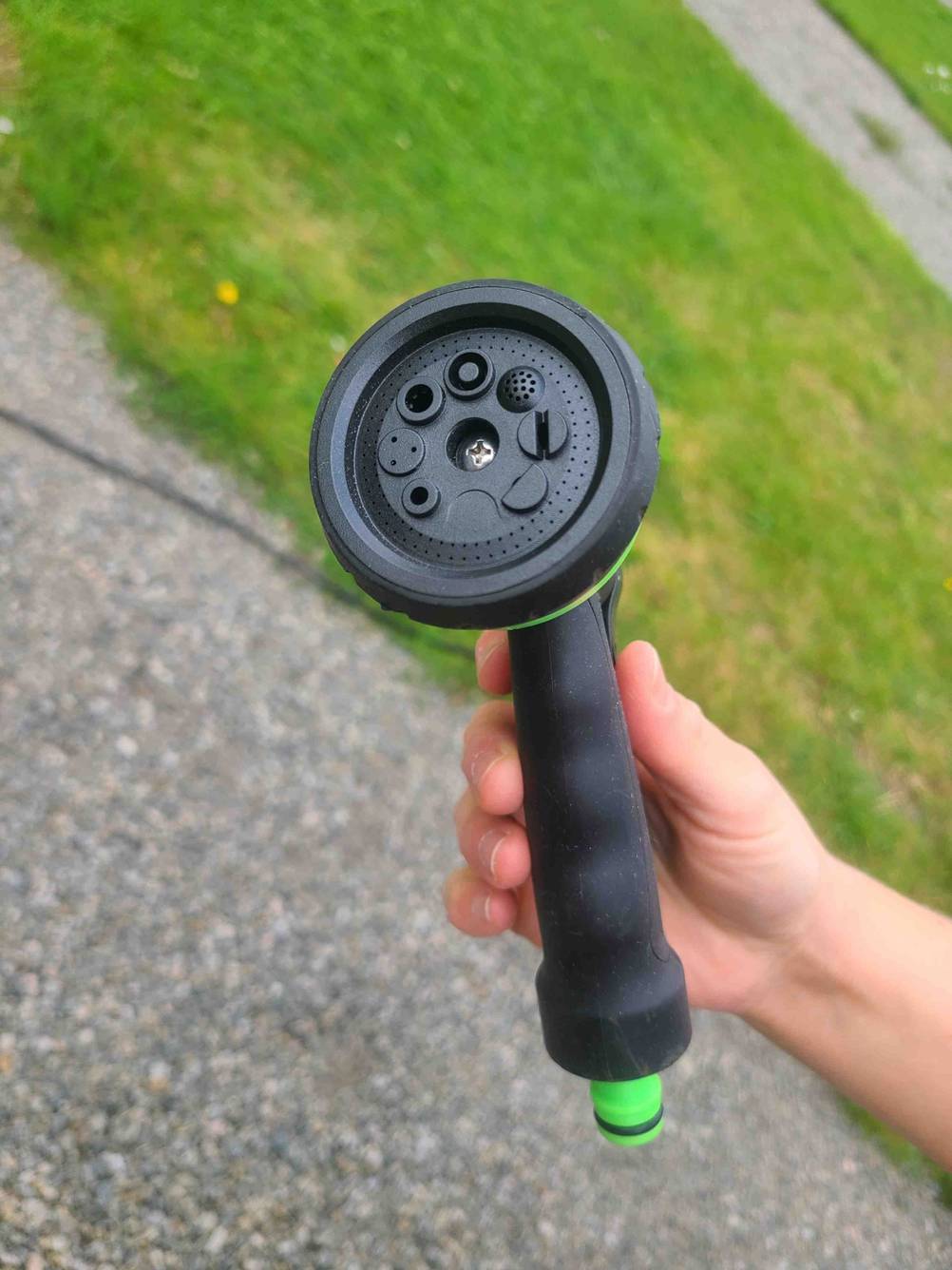 Die Brause des getesteten Spiral-Gartenschlauchs wird in der Hand gehalten.