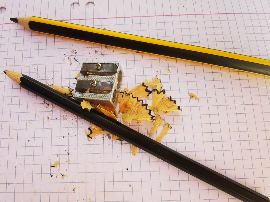 Ein Doppel-Anspitzer im Test liegt zwischen zwei angespitzten Stiften auf dem Rechnerpapier.
