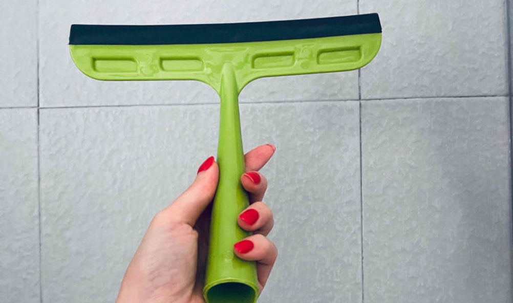 Fensterputzer-Test: grüner Fensterputzer wird vor Fliesen gehalten.