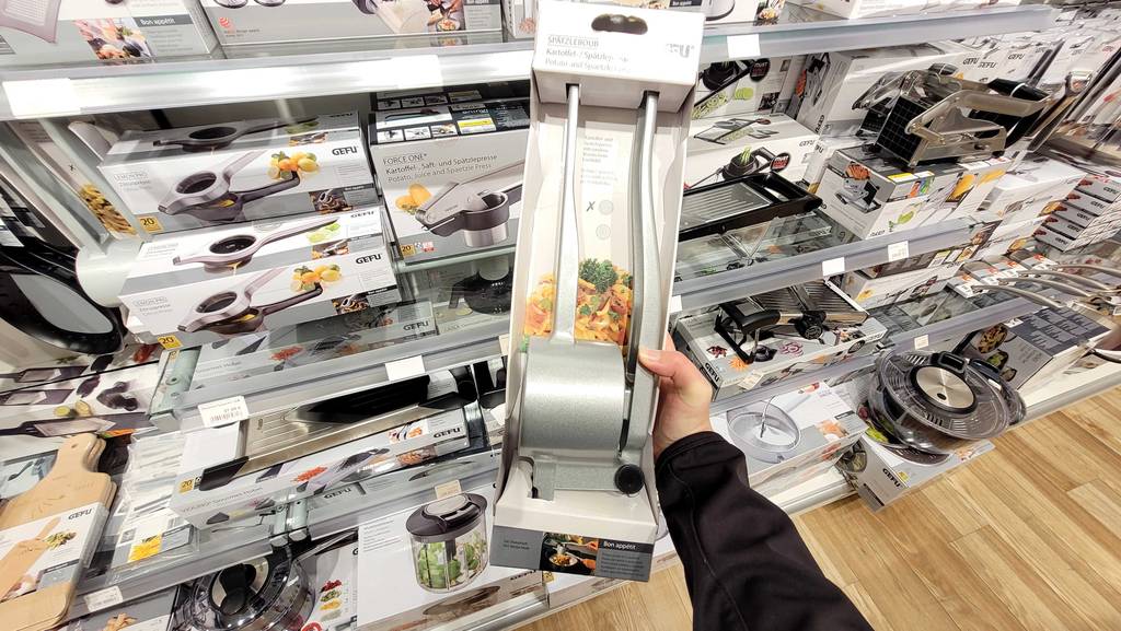 Die getestete Spätzlepresse wird in der Verpackung in der Hand gehalten.