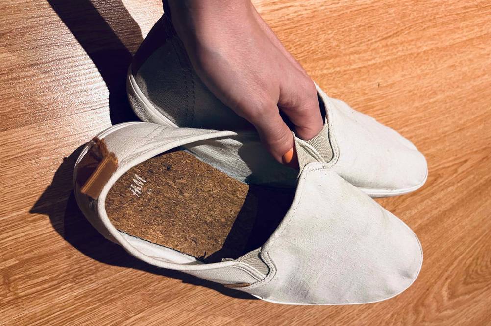 Im Test: Eine Hand stellt ein Paar Espadrilles für Herren auf einen Holzboden.
