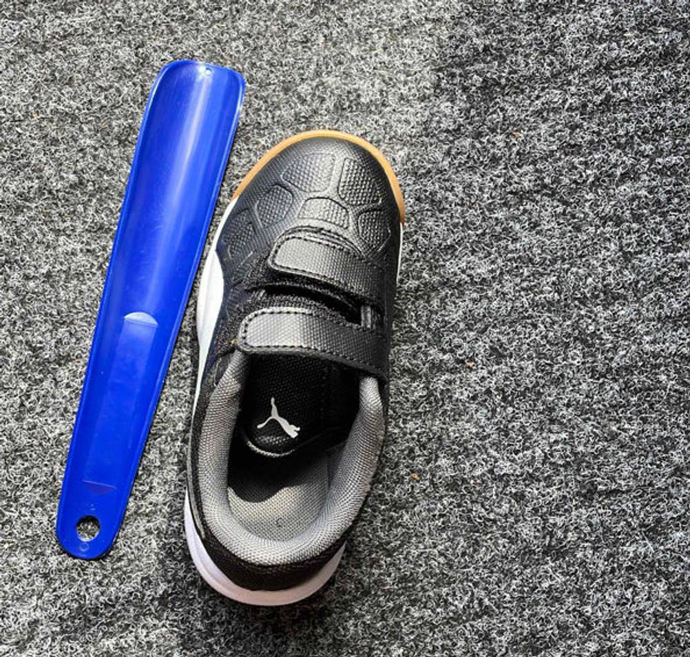 Schuhlöffel-Test: ein blauer Schuhlöffel liegend neben einem Kinderschuh.