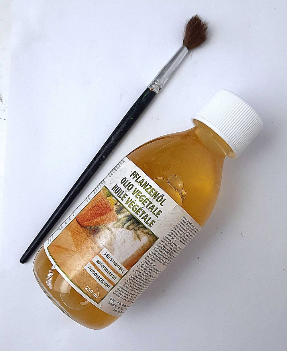 Das getestete Holzöl liegt neben einem Haarpinsel.