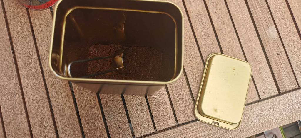 Kaffeedose mit Inhalt und Kelle auf einer Holzfläche