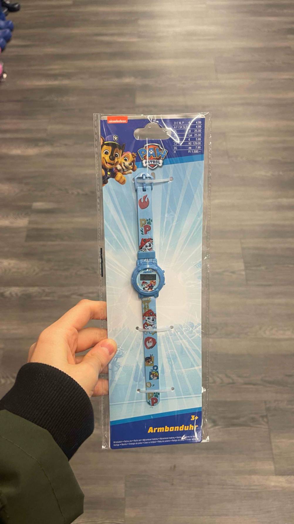 Die getestete Kinderuhr mit einem Motiv von Paw Patrol wird in einem Geschäft in der Hand gehalten.