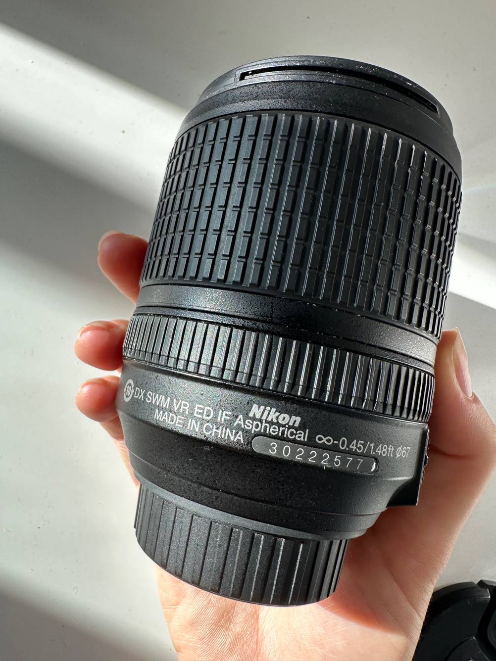 Im Test: Eine Hand hält ein Nikon-Objektiv vor eine helle Wand.