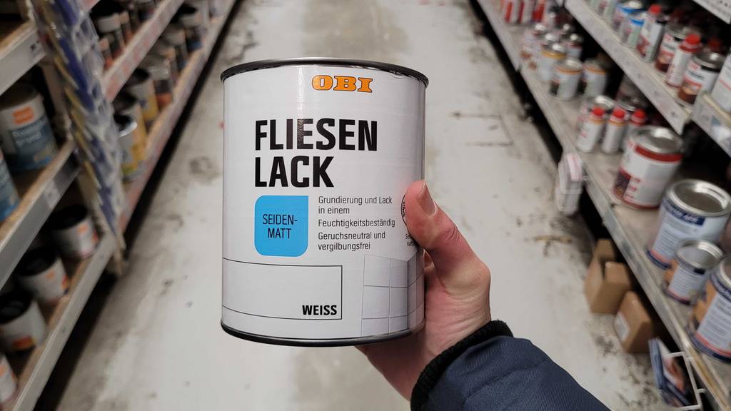 Ein getesteter Fliesenlack in seiden-matt wird in der Hand gehalten.