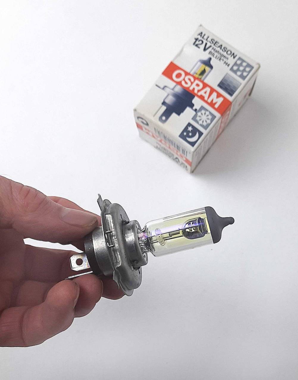 Die getestete H4-Lampe wird vor der dazugehörigen Verpackung gehalten.