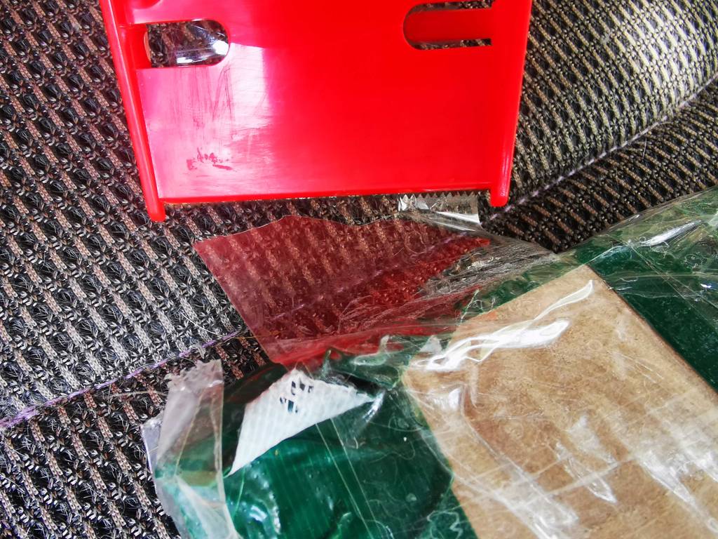 Pakentbandroller-Test: Ein rotes Modell liegt auf einer grauen Matte neben einem transparenten Paketband.