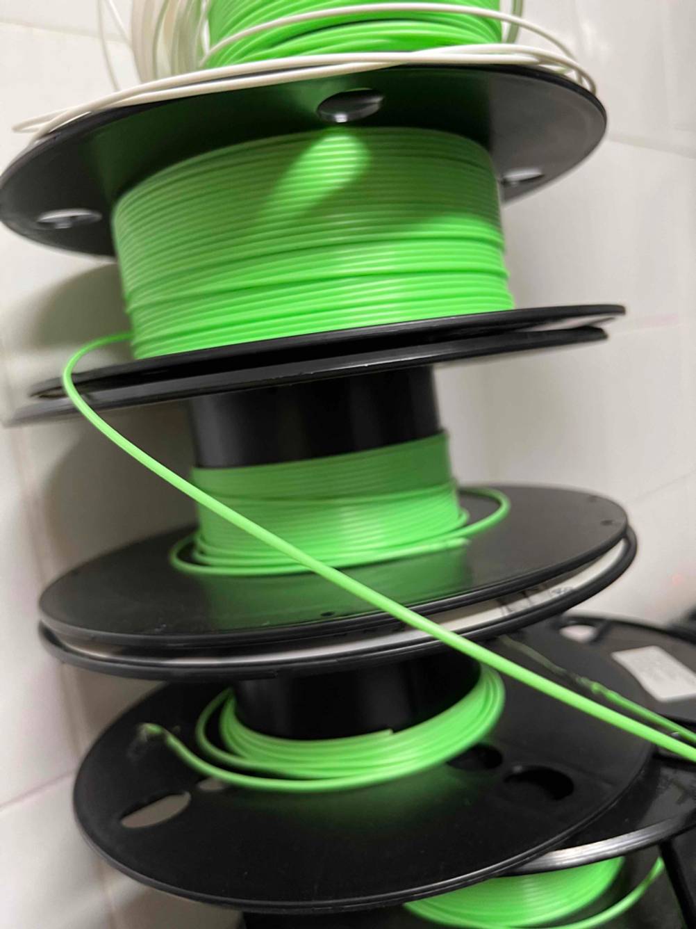 Im Test: Mehrere gestapelte Rollen 3D-Drucker-Filament an einer Wand.